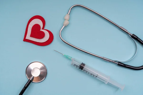 Medizinische Werkzeuge Stethoskop, Spritzen mit Herz auf blauem Hintergrund. — Stockfoto