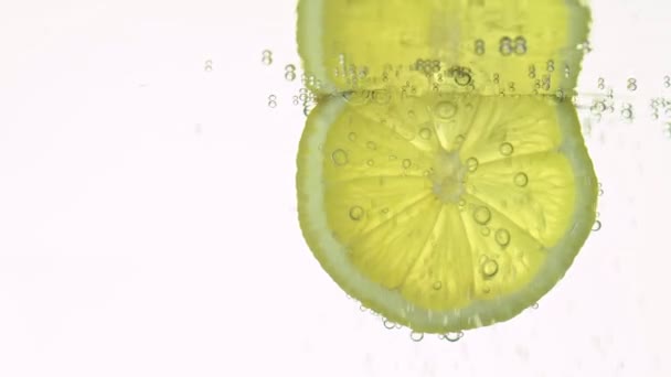 Il concetto di freschezza, una fetta di limone in acqua limpida, con bollicine rinfrescanti, primo piano. Bevande agli agrumi. — Video Stock