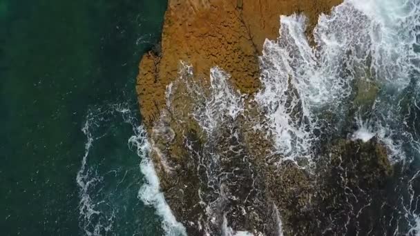 Vídeo aéreo nostálgico, en cámara lenta del mar, las olas rodan suavemente a orillas rocosas del Océano Atlántico Pacífico. — Vídeos de Stock