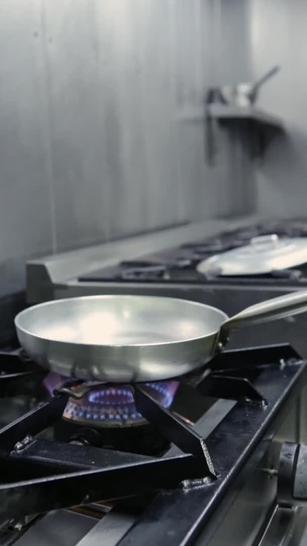 La sartén se calienta a fuego alto para cocinar, en una estufa de gas. Vídeo vertical. Primer plano . — Vídeos de Stock