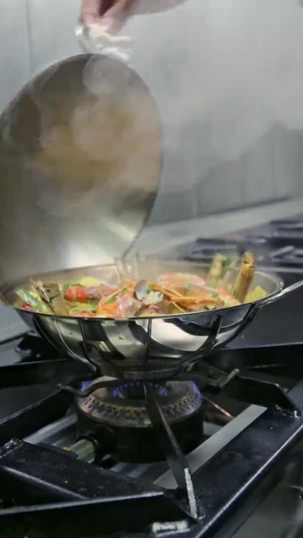 Le chef retire le couvercle du cataplan, qui est cuit sur une cuisinière à gaz. Vidéo verticale. Gros plan. — Video