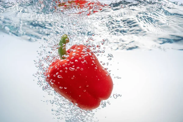 Padající červená paprika v ekologicky čisté vodě. Detailní záběr. — Stock fotografie