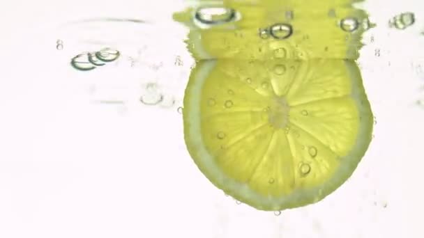 Het concept van versheid, een schijfje citroen in helder water, met verfrissende gasbellen, close-up. Citrusvruchten. — Stockvideo