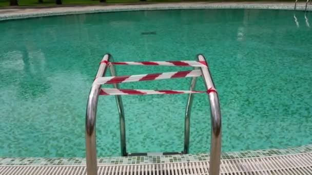 Las barandillas de la piscina del hotel, envueltas con una cinta de advertencia que prohíbe la entrada en ella durante el coronovirus, virus . — Vídeos de Stock