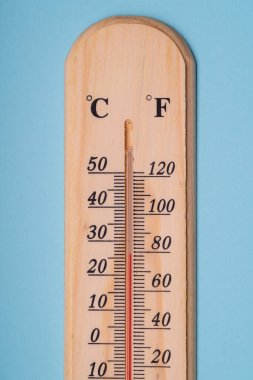 Mavi arka plandaki sıcaklığı ölçmek için klasik ahşap termometre. Yakın plan..