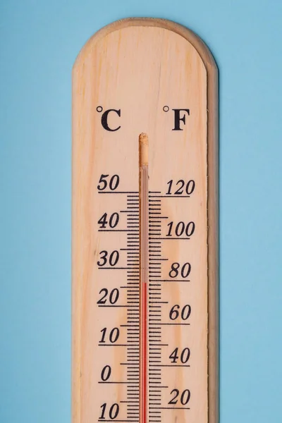 Termômetro de madeira clássico para medir a temperatura em um fundo azul. Close-up . — Fotografia de Stock