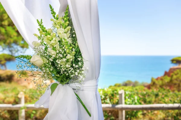 Bellissimo bouquet da sposa in tulle, legato con un nastro, sullo sfondo dell'oceano. Primo piano . — Foto Stock
