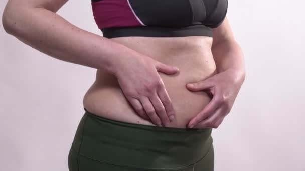 Kobieta w średnim wieku z obwisłą skórą trzęsie dużym brzuchem, na białym tle. Plan dodatkowy. — Wideo stockowe