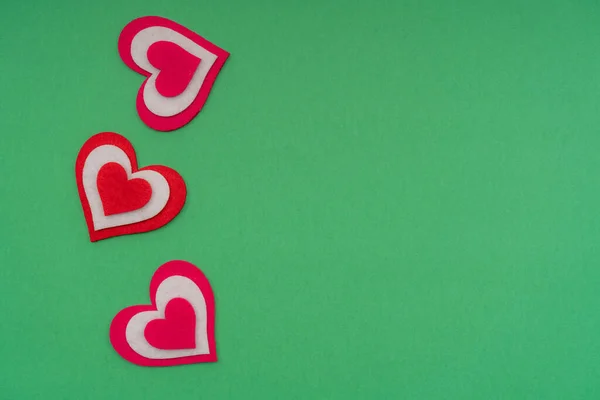 Verticale rode harten op een groene achtergrond. Kopieerruimte. — Stockfoto