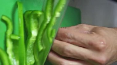 Ekolojik taze yeşil biber, aşçı tarafından, vejetaryen salata pişirmek için dilimlenir. Dikey video.