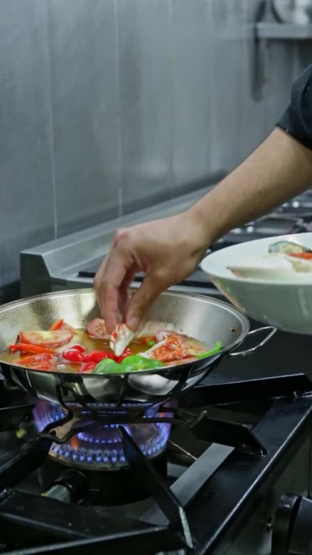 Chef koken een kataplan met zeevruchten in brand, op een gasfornuis. Verticale video. Close-up. — Stockvideo