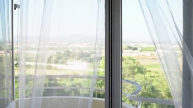 Doğa manzarası, pencereden manzara. Hafif rüzgar tülleri sallıyor. Yüksek anahtar. Aşırı pozlama.