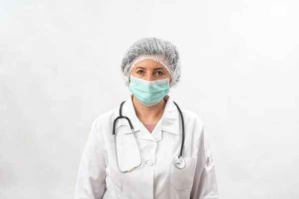 Medico femminile stanco, infermiera in attrezzature protettive e una maschera da virus, su uno sfondo bianco. Con uno stetoscopio. — Foto Stock