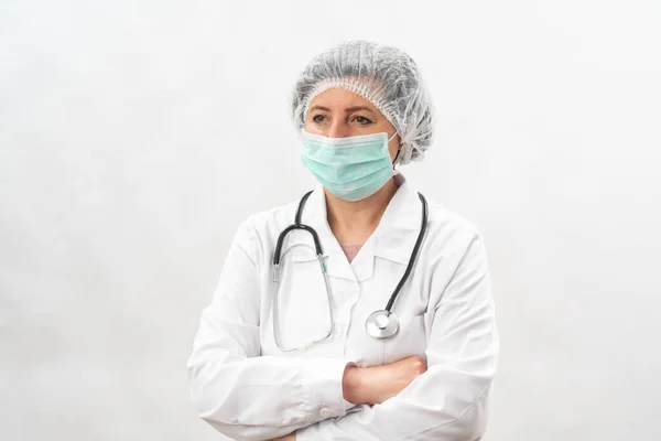 Médico feminino cansado, enfermeira em equipamento de proteção e uma máscara de vírus, em um fundo branco. Com um estetoscópio . — Fotografia de Stock