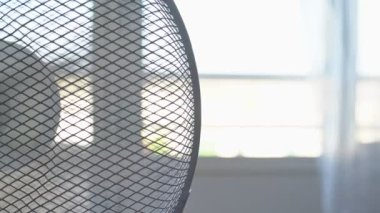 Yazın odayı soğutmak için elektrikli vantilatör, sıcak. Arka plan bulanık. Aşırı maruz kalma. Yüksek tuş.