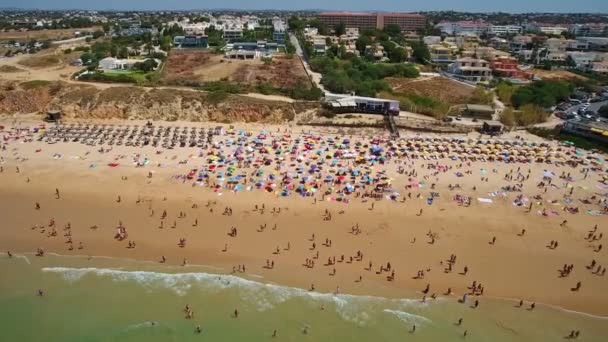Flygfoto av kusten, stränder i Gale i Portugal Turister vila under paraplyer, simma i klart, turkost vatten. Långsamma rörelser. — Stockvideo