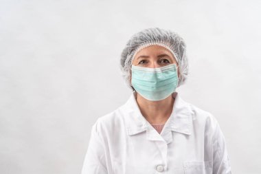 Yorgun kadın doktor, koruyucu ekipman hemşiresi ve beyaz bir arka planda virüs maskesi..