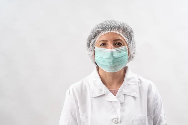 Medico femminile stanco, infermiera in attrezzature protettive e una maschera da virus, su uno sfondo bianco. Foto Stock Royalty Free