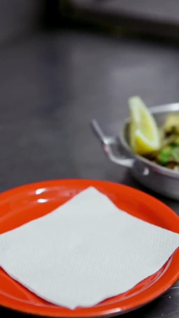 Almeja apetecible con ajo, hierbas, dispuestos en un plato de aluminio, con solo un limón, el chef pone en un plato rojo. Vídeo vertical. Primer plano . — Vídeos de Stock