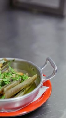 Sarımsaklı, otlu, alüminyum bir tabağa serilmiş, bir düzine limonla süslenmiş iştah açıcı midye. Dikey video. Yakın plan..