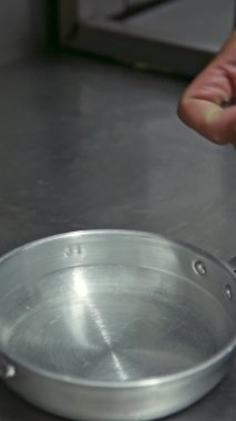 Şef istiridyeyi sarımsak ve otlarla birlikte alüminyum bir tabağa koyar. Dikey video. Yakın plan..