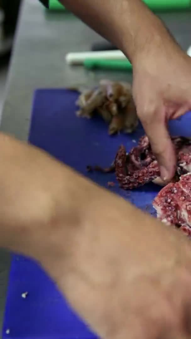 Chef cuisinier partage une pieuvre cuite avec un couteau. Vidéo verticale. Gros plan. — Video