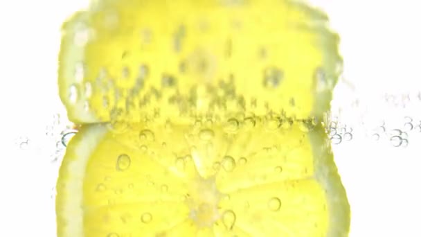 Het concept van versheid, een schijfje citroen in helder water, met verfrissende gasbellen, close-up. Citrusvruchten. — Stockvideo