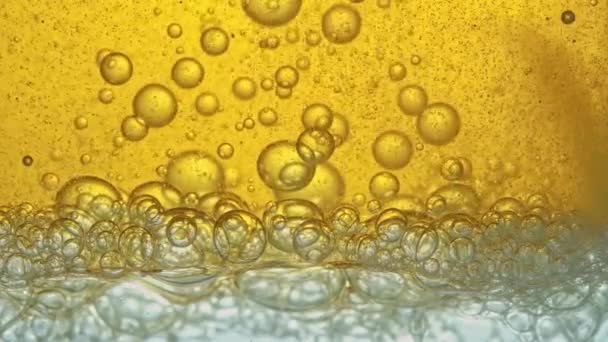 Treibstoff, gelbes, goldenes Öl, das in einem Labor in ein Glasgefäß gegossen wird, setzt Schaumstoffblasen frei. — Stockvideo