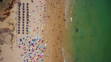 Sahildeki hava fotoğrafçılığı, Portekiz 'deki Gale plajları. Turistler şemsiyelerin altında dinleniyor, berrak yüzüyorlar, resifli turkuaz su..