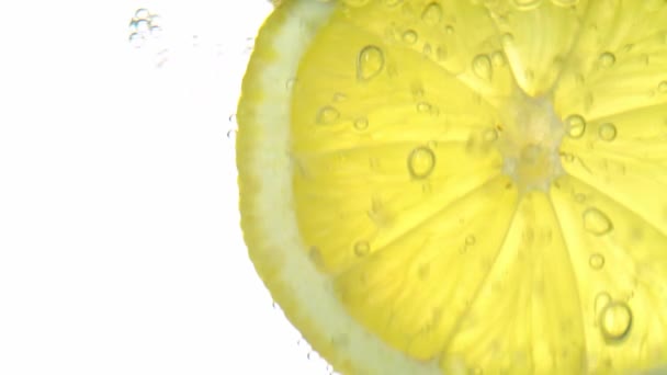 O conceito de frescura, uma fatia de limão em água clara, com bolhas de gás refrescantes, close-up. Bebidas cítricas. — Vídeo de Stock