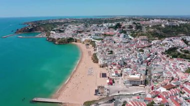 Panoramik hava manzarası albufeiras çarpıcı kıyı manzarasını gözler önüne seriyor, turkuaz sular, kumlu plajlar, Portekiz 'deki resim gibi kıyı şeridi boyunca yerleşmiş kentsel mimari. Albufeira Portekiz 15.06.2025