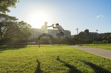 Güneşli bir parkta senkronize dövüş sanatları sıçraması.