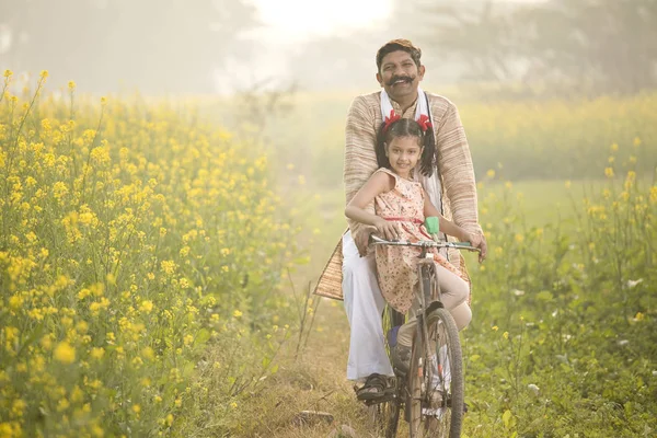父亲与女儿骑自行车在农业领域 — 图库照片