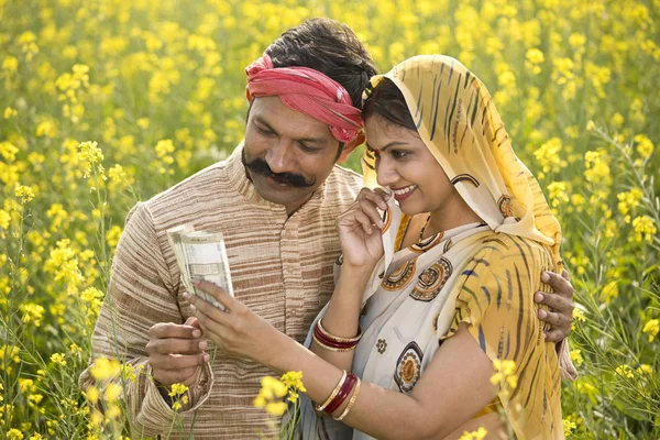在农业领域持有印度卢比钞票的农村夫妇 — 图库照片