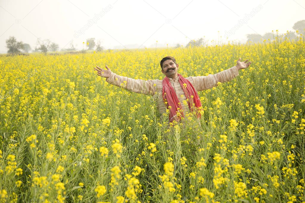 Farmer with arms outstretched in rapeseed field