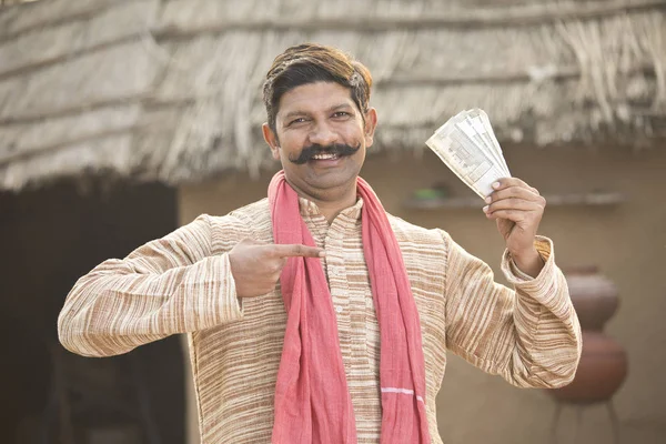Excited farmer holding Indian rupee notes and screaming