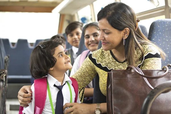 Professora feliz cuidando da estudante enquanto viaja no ônibus escolar — Fotografia de Stock