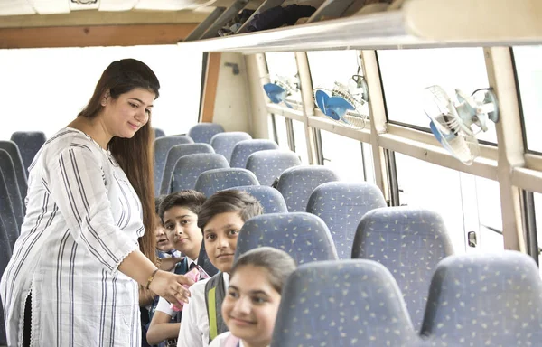 Professor cuidando de crianças enquanto viaja no ônibus escolar — Fotografia de Stock