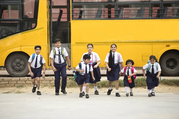 Iskolások és Iskoláslányok séta az iskolabusz — Stock Fotó