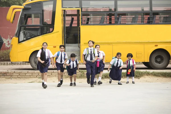 Estudantes e alunas caminhando do ônibus escolar — Fotografia de Stock