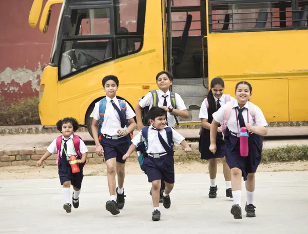 Estudantes e alunas caminhando do ônibus escolar — Fotografia de Stock