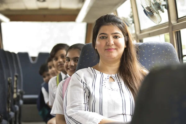 Boldog tanár gondozása iskoláslány utazás közben az iskolabusz — Stock Fotó
