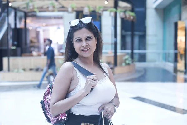 Mujer alegre sosteniendo bolsas de compras en el centro comercial — Foto de Stock