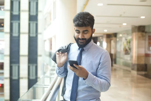 Young businessman holding mobile phone at cafeteria