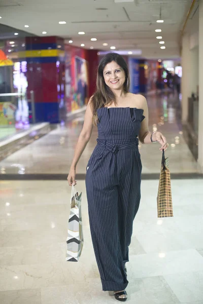 Mujer alegre sosteniendo bolsas de compras en el centro comercial — Foto de Stock