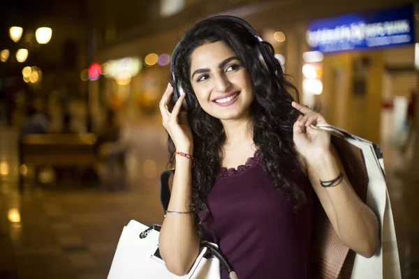 晚上在城市里用耳机玩乐的时髦女人 — 图库照片