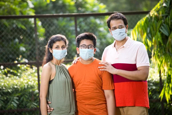 Family with protective face mask at park