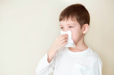 Çocuk burnunu sildi. Peçeteli hasta çocuk. Alerjik çocuk, grip mevsimi. Soğuk Rhinitis 'li çocuk, soğuk sümük burunlu olsun. virüs ve enfeksiyon