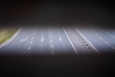 Pistte ileri ve sol ok. Siyah asfalta beyaz ok işareti. Taşımacılık arka planı. Üç şeritli modern asfalt yol.