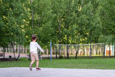 Çocuk parkta koşar. Sahnedeki çocuk. Parkta basketbol ağı